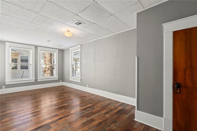 empty room featuring a drop ceiling and dark wood-type flooring