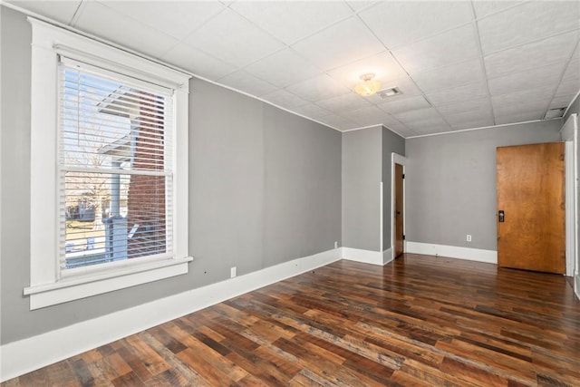 spare room with dark wood-type flooring and a paneled ceiling