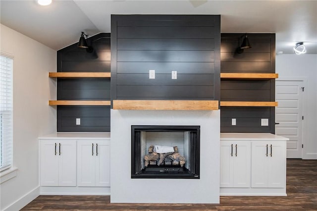 kitchen with white cabinetry, a large fireplace, vaulted ceiling, and dark hardwood / wood-style floors