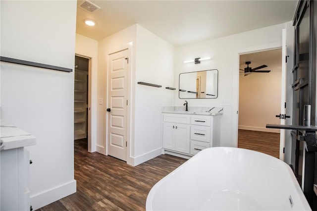 bathroom with ceiling fan, a tub to relax in, wood-type flooring, and vanity