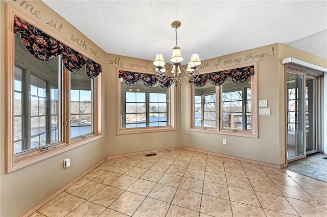 unfurnished dining area with a chandelier, a textured ceiling, and light tile patterned floors