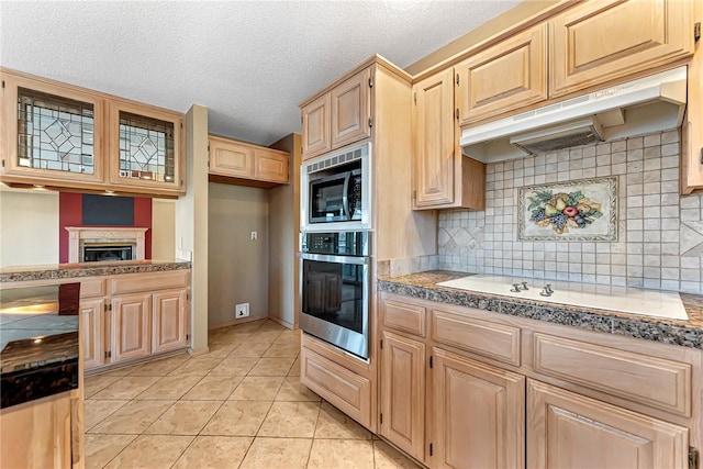 9 Marykirk Ln, Bella Vista, AR 72715 - kitchen with stainless steel appliances, under cabinet range hood, light brown cabinets, backsplash, and a textured ceiling