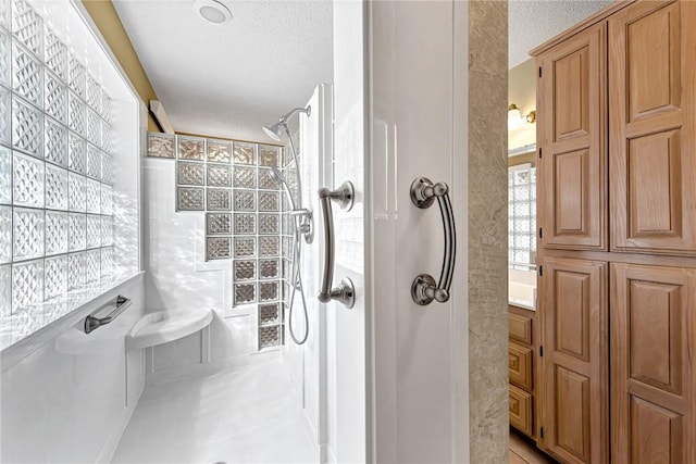 bathroom with a tile shower, a textured ceiling, and tile walls