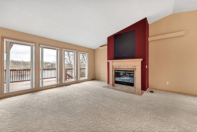 unfurnished living room featuring lofted ceiling, a healthy amount of sunlight, a high end fireplace, and carpet flooring