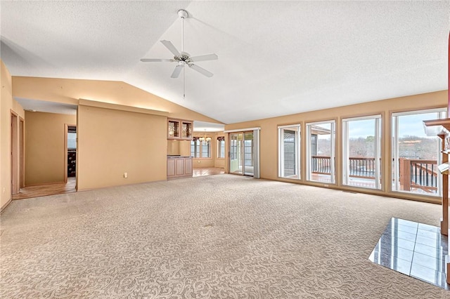 unfurnished living room featuring a textured ceiling, vaulted ceiling, ceiling fan, and carpet flooring