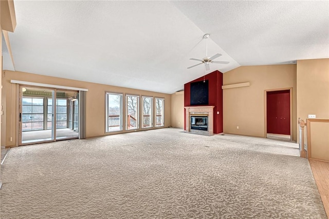 unfurnished living room with ceiling fan, carpet flooring, vaulted ceiling, and a textured ceiling