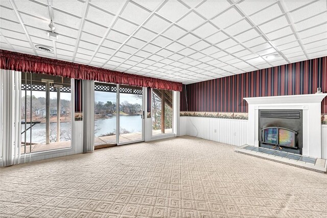 unfurnished living room featuring a water view and carpet flooring