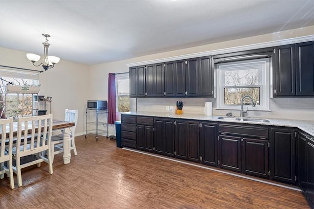 kitchen featuring pendant lighting, sink, dark hardwood / wood-style flooring, a notable chandelier, and light stone counters