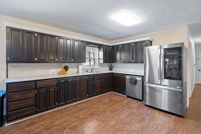 kitchen featuring dark hardwood / wood-style floors, sink, stainless steel appliances, light stone countertops, and dark brown cabinets