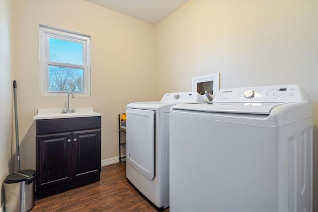 washroom with sink, dark wood-type flooring, washing machine and dryer, and cabinets