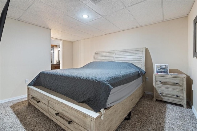 bedroom with a drop ceiling and dark colored carpet