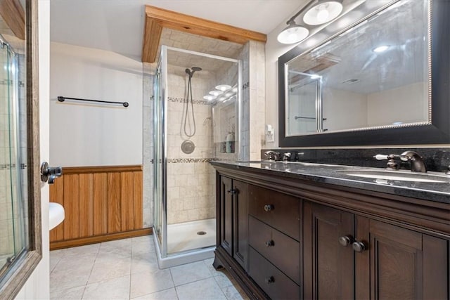 bathroom with vanity, tile patterned flooring, wooden walls, and a shower with shower door