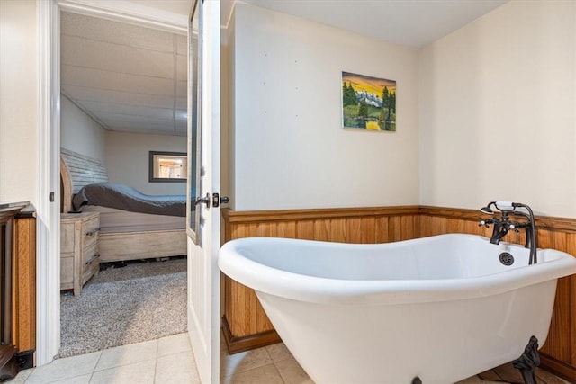 bathroom with tile patterned flooring, a bathtub, and wooden walls