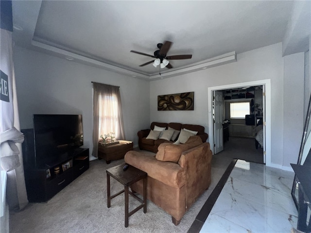 living room featuring a tray ceiling and ceiling fan