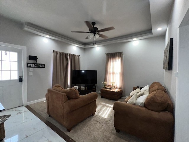 living room with ceiling fan and a tray ceiling