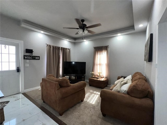 living room with a tray ceiling and ceiling fan