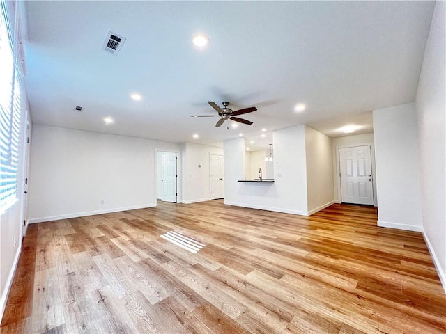 unfurnished living room featuring ceiling fan, sink, and light wood-type flooring