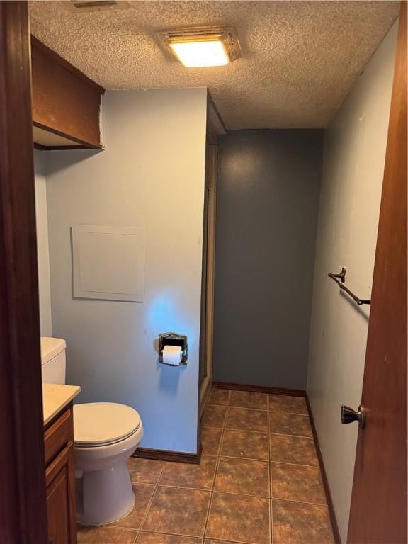 bathroom featuring vanity, tile patterned flooring, toilet, and a textured ceiling