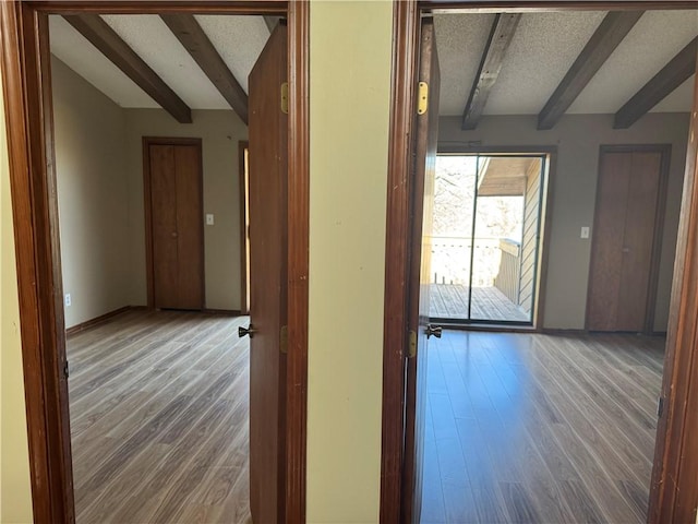 corridor featuring wood-type flooring, beam ceiling, and a textured ceiling