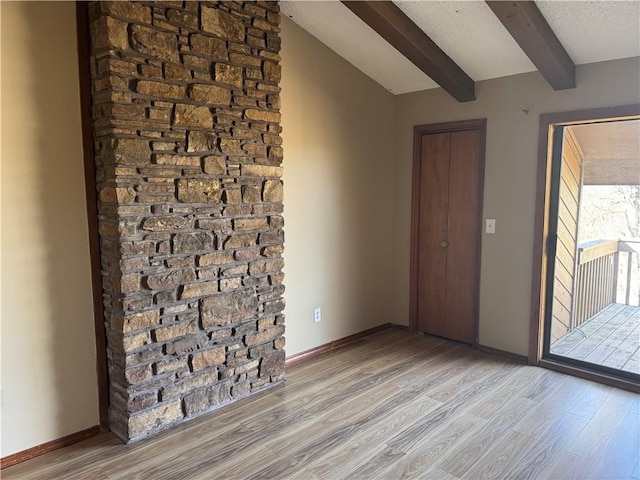 entryway featuring lofted ceiling with beams, a textured ceiling, and light wood-type flooring