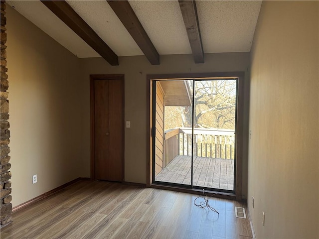 entryway featuring a textured ceiling, light hardwood / wood-style floors, and beamed ceiling