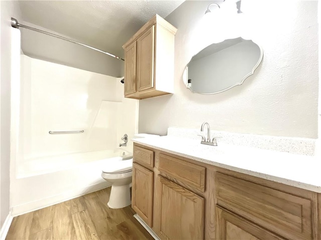 full bathroom with hardwood / wood-style flooring, shower / bath combination, vanity, toilet, and a textured ceiling