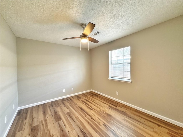 empty room with wood finished floors, baseboards, ceiling fan, and a textured ceiling