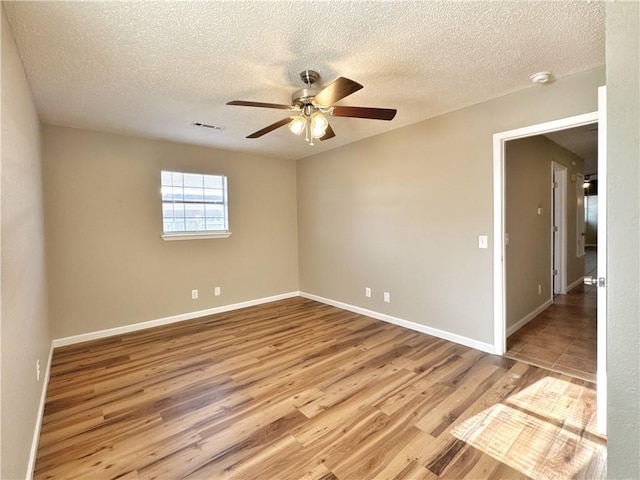 empty room featuring ceiling fan, light hardwood / wood-style floors, and a textured ceiling