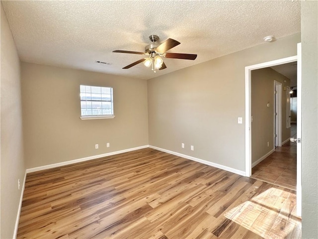 spare room with ceiling fan, light hardwood / wood-style flooring, and a textured ceiling