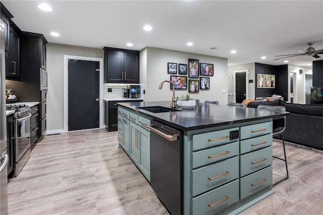 kitchen featuring appliances with stainless steel finishes, sink, a kitchen breakfast bar, a kitchen island with sink, and light wood-type flooring