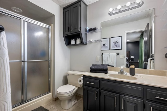 bathroom with tile patterned flooring, vanity, a shower with door, and toilet