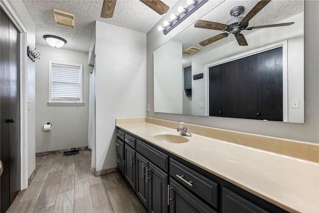 bathroom featuring hardwood / wood-style flooring, ceiling fan, vanity, and a textured ceiling