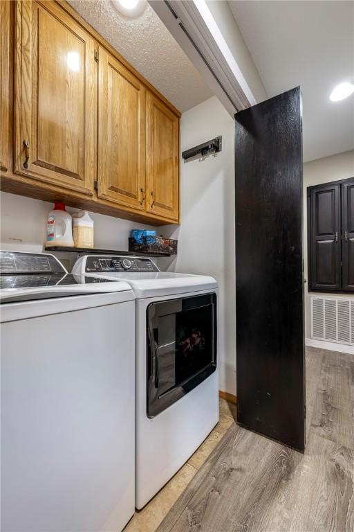 laundry room with cabinets, light hardwood / wood-style flooring, and washing machine and clothes dryer