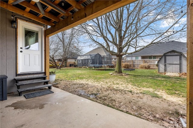 view of yard featuring a trampoline, a patio area, and a storage unit