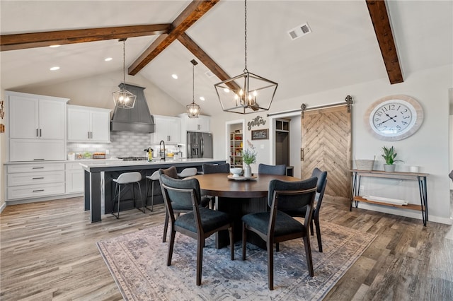 dining room with hardwood / wood-style floors, lofted ceiling with beams, and a barn door