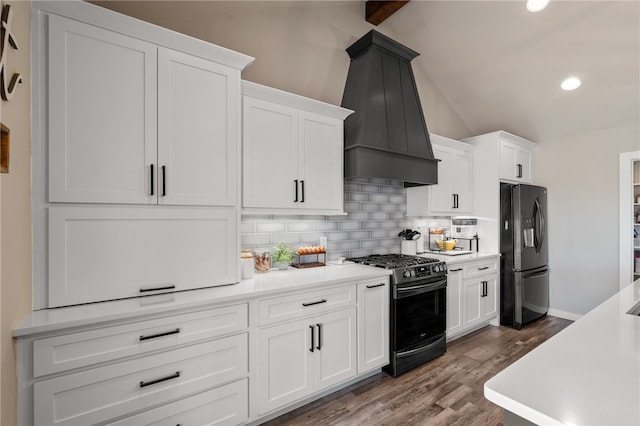 kitchen featuring lofted ceiling, premium range hood, white cabinets, black fridge, and range with gas cooktop