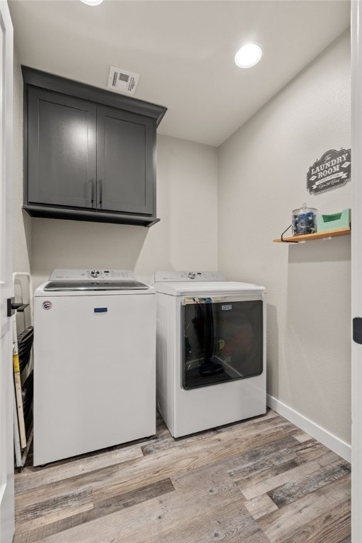 washroom with separate washer and dryer, cabinets, and light wood-type flooring