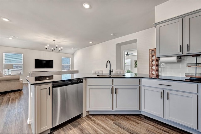 kitchen with a wealth of natural light, sink, backsplash, stainless steel dishwasher, and kitchen peninsula