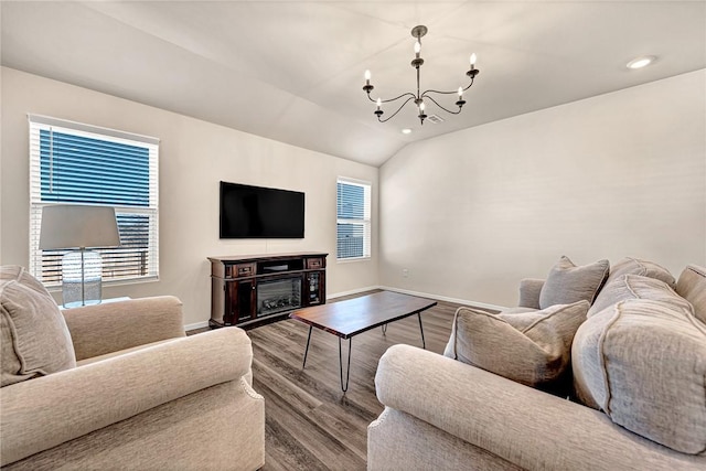 living room featuring lofted ceiling, a notable chandelier, hardwood / wood-style flooring, and plenty of natural light