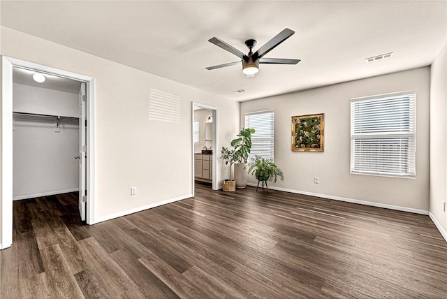 unfurnished bedroom featuring dark hardwood / wood-style floors, a walk in closet, a closet, and ceiling fan