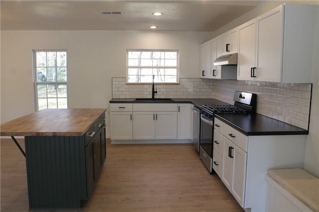 kitchen with sink, butcher block countertops, light wood-type flooring, appliances with stainless steel finishes, and white cabinets