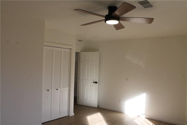 unfurnished bedroom with wood-type flooring, a closet, and ceiling fan