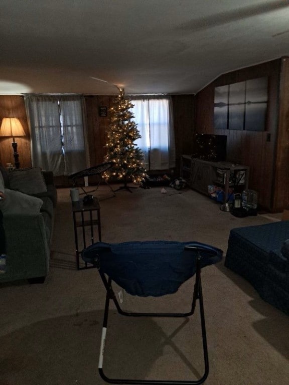 carpeted living room featuring wood walls