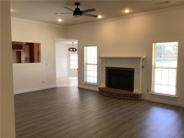 unfurnished living room featuring dark hardwood / wood-style flooring, a brick fireplace, ornamental molding, and ceiling fan