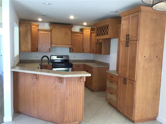 kitchen with a kitchen bar, stainless steel gas range, sink, and kitchen peninsula