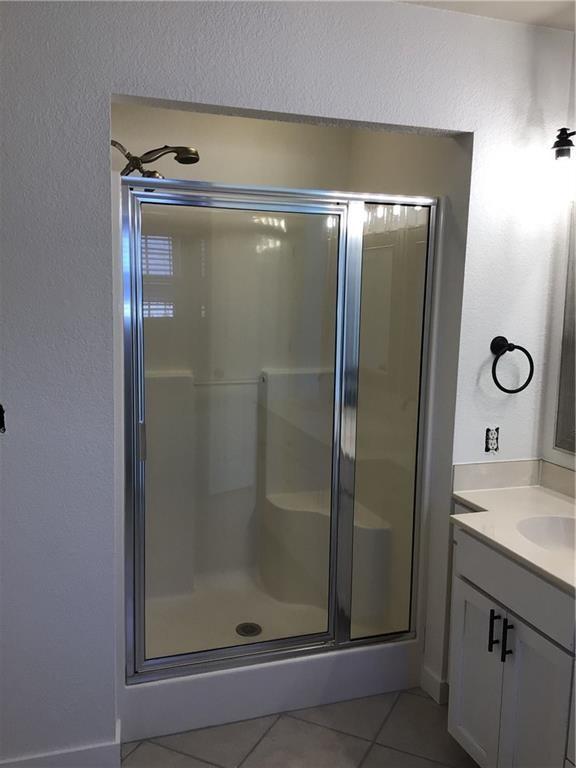 bathroom with tile patterned flooring, vanity, and a shower with shower door