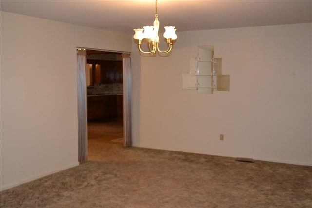 empty room featuring carpet flooring and a chandelier