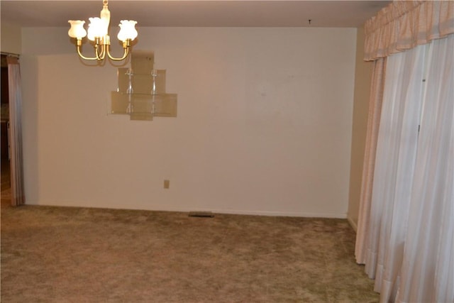 spare room featuring carpet and an inviting chandelier