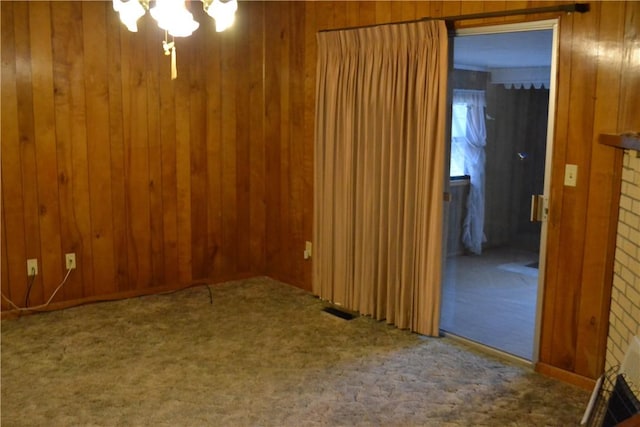 carpeted spare room with wood walls