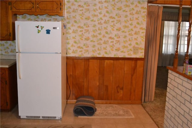 kitchen featuring white refrigerator and wooden walls